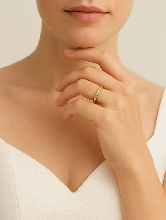 Close-up of a person wearing a gold ring on a neutral background