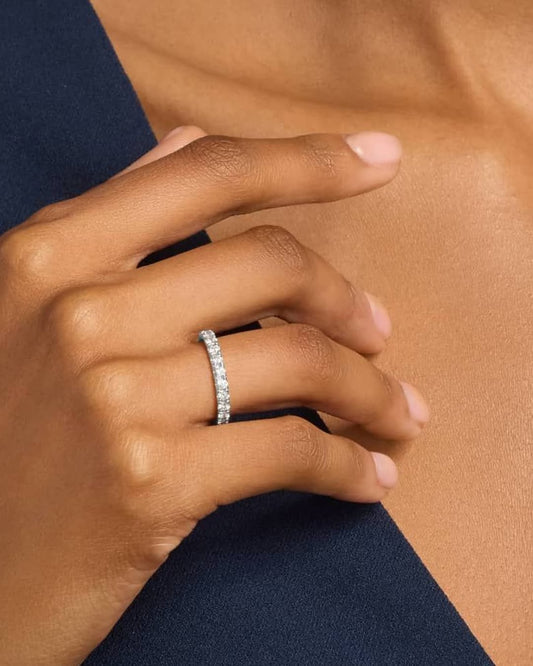 A person's hand displaying a 2MM wide 10 karat gold band ring with a cubic zirconia gemstone.