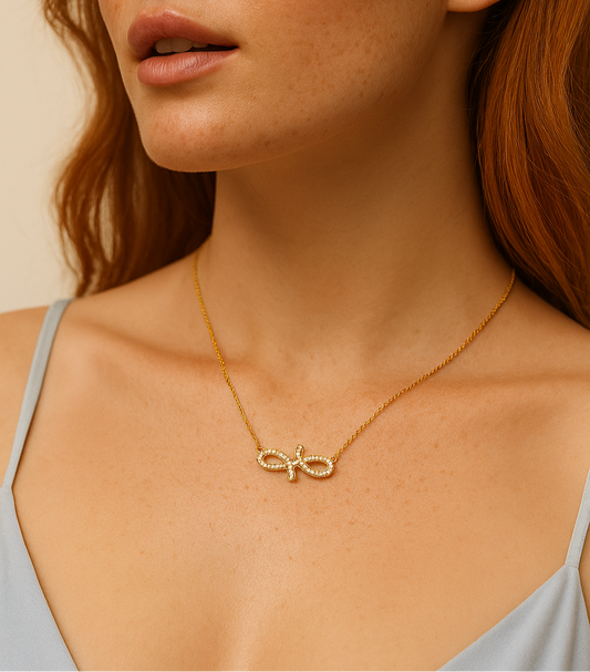 Woman wearing a gold necklace with a delicate pendant against a neutral background