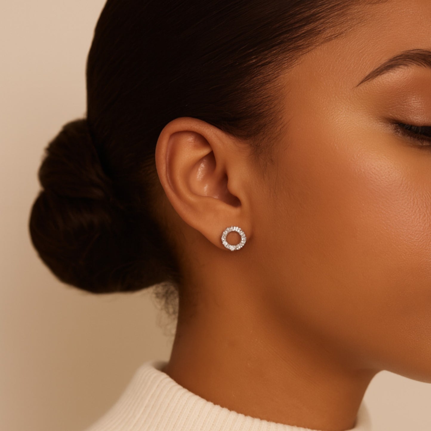Close-up of a woman wearing silver hoop earrings with a neutral background