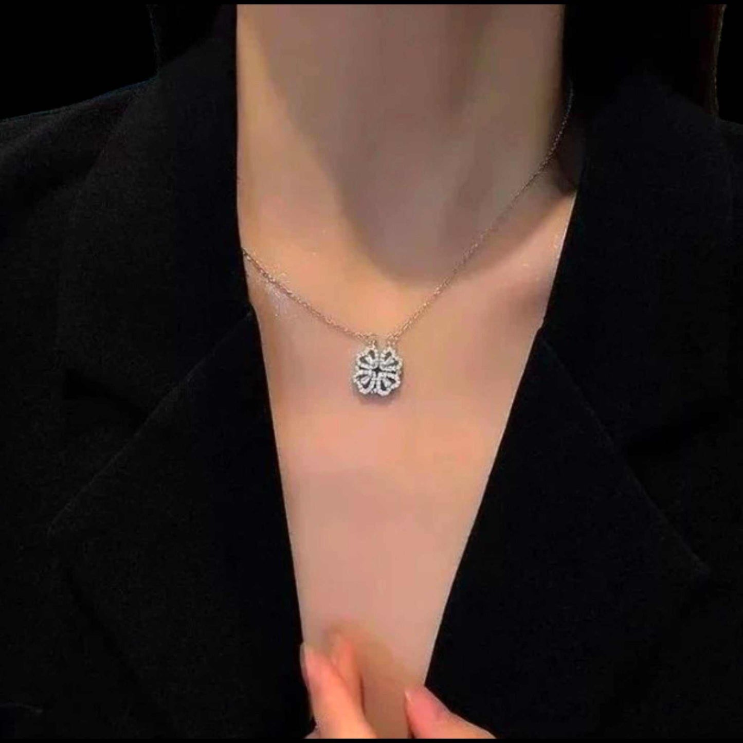 Necklace with a floral pendant on a person wearing a black blazer.