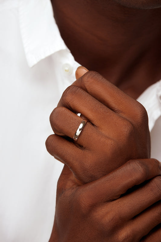 A close-up image of a man's hand wearing a 4MM Comfort Fit Band in 10K Gold on his finger.