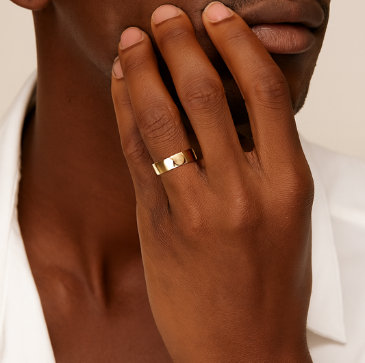 Close-up of a hand with a gold ring on a neutral background