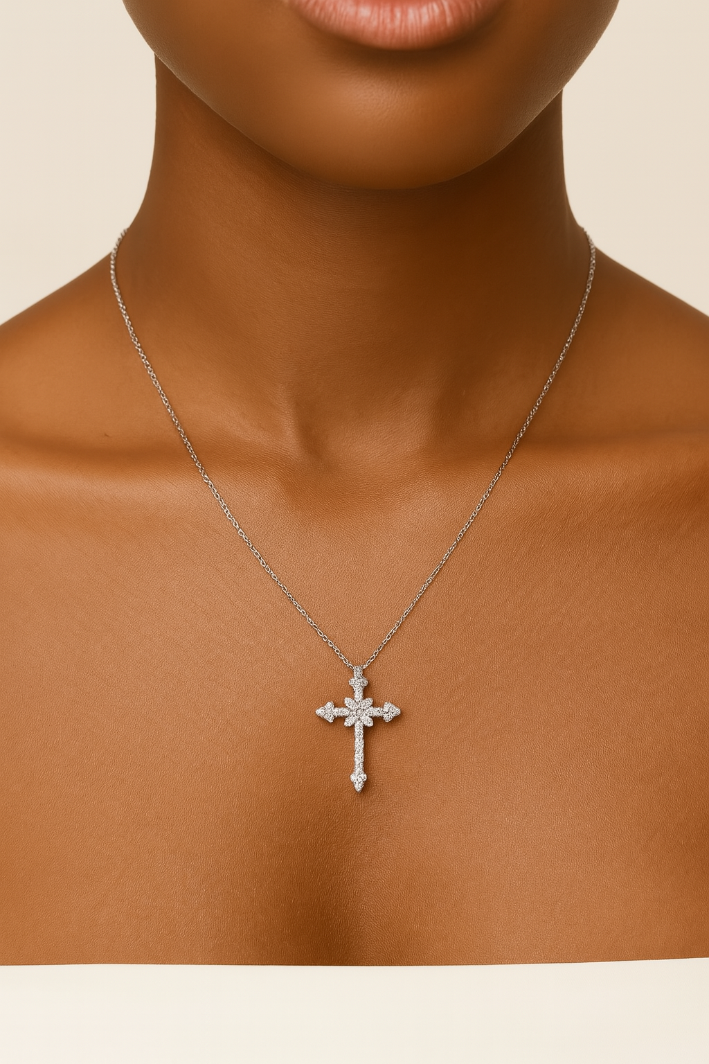 Silver cross necklace on a person against a neutral background