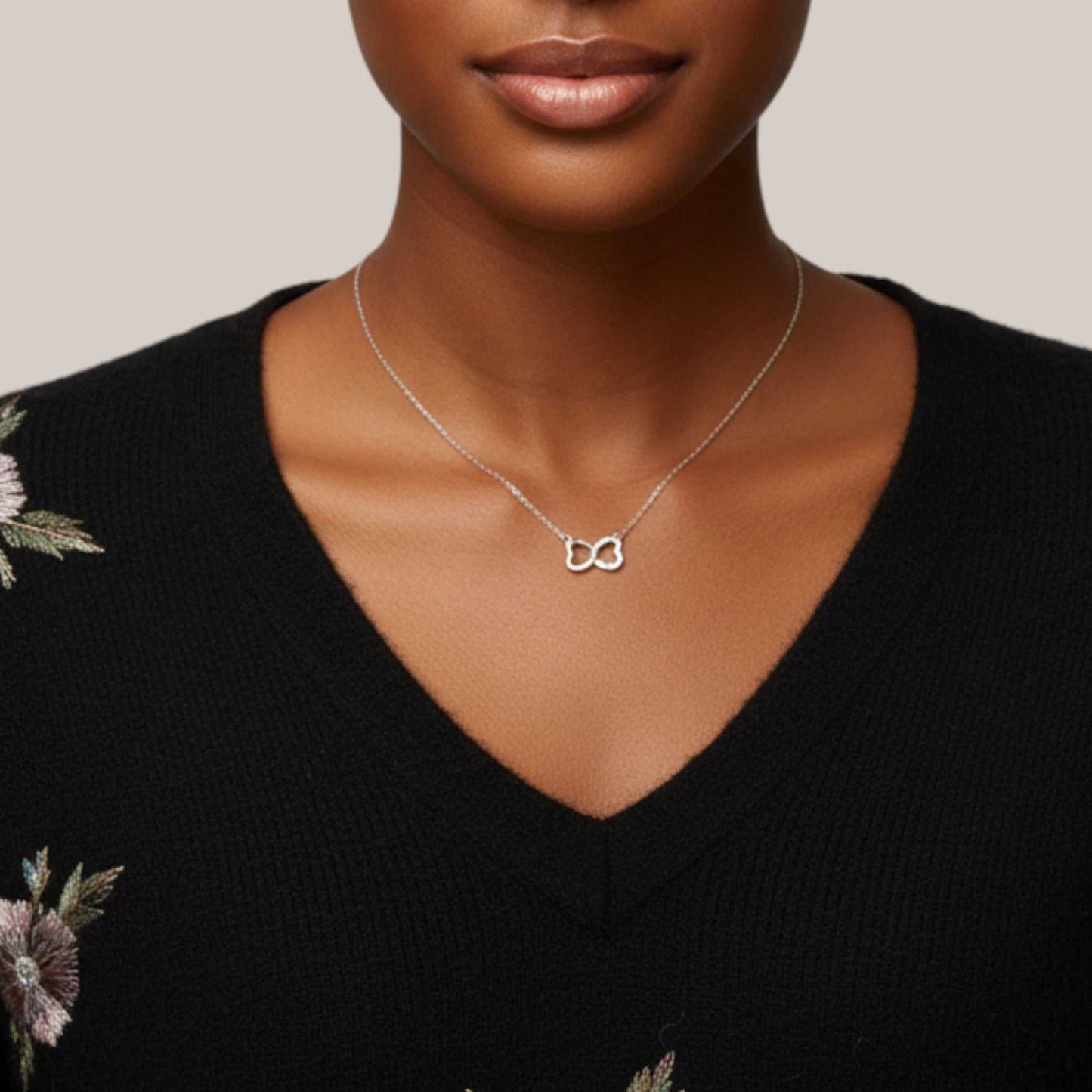 Woman wearing a silver necklace with a unique pendant against a neutral background