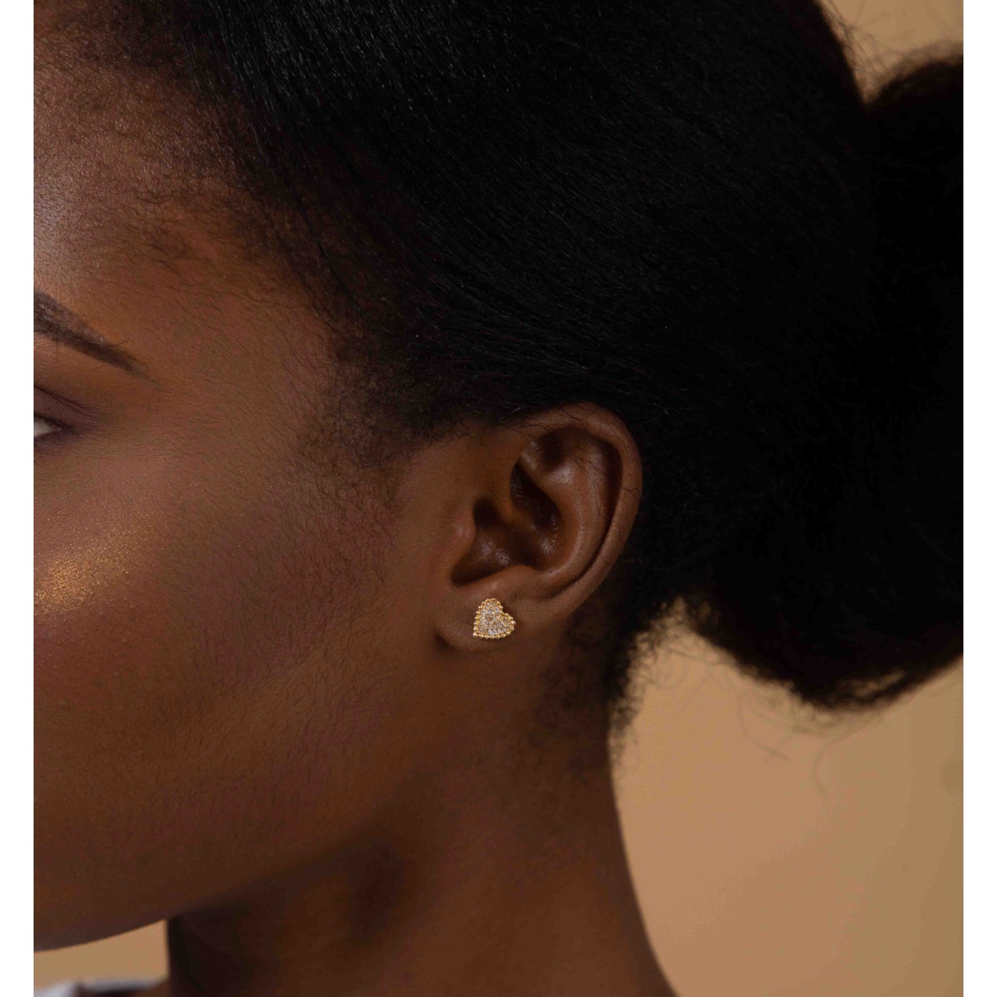 Close-up of an ear wearing a heart-shaped earring with a blurred background
