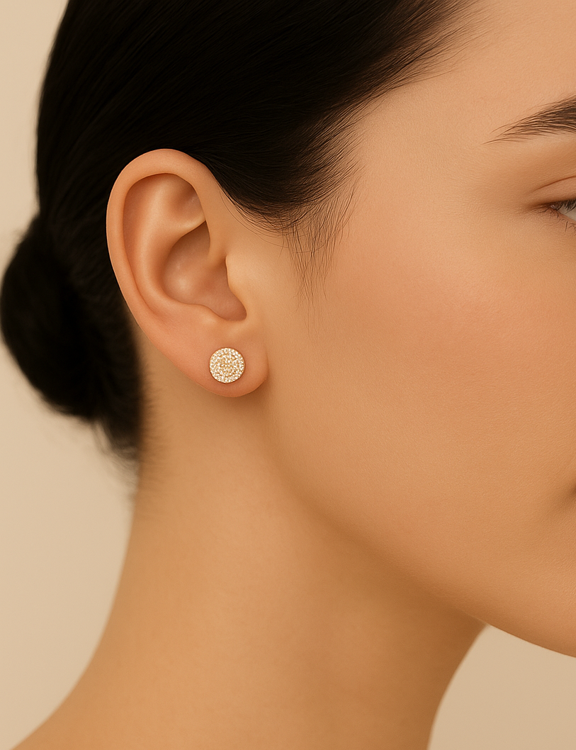 Close-up of a woman wearing a small round earring against a beige background