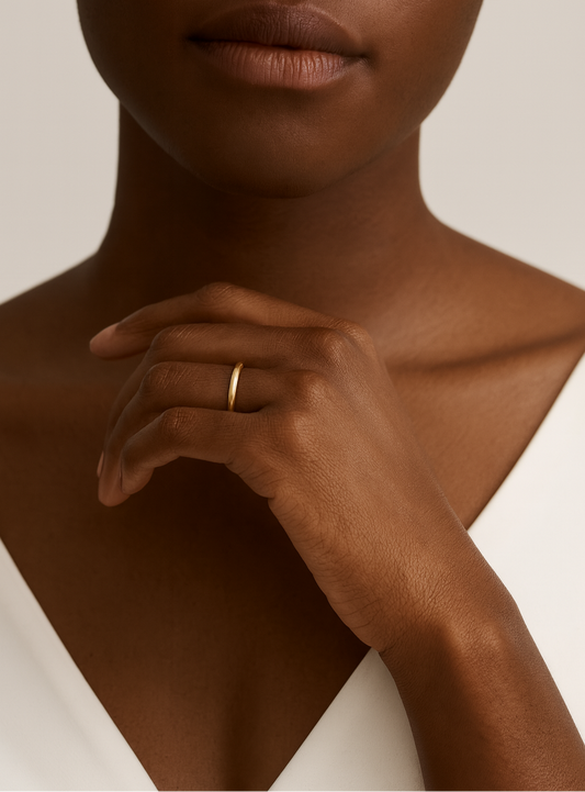 Close-up of a person wearing a gold ring on a neutral background