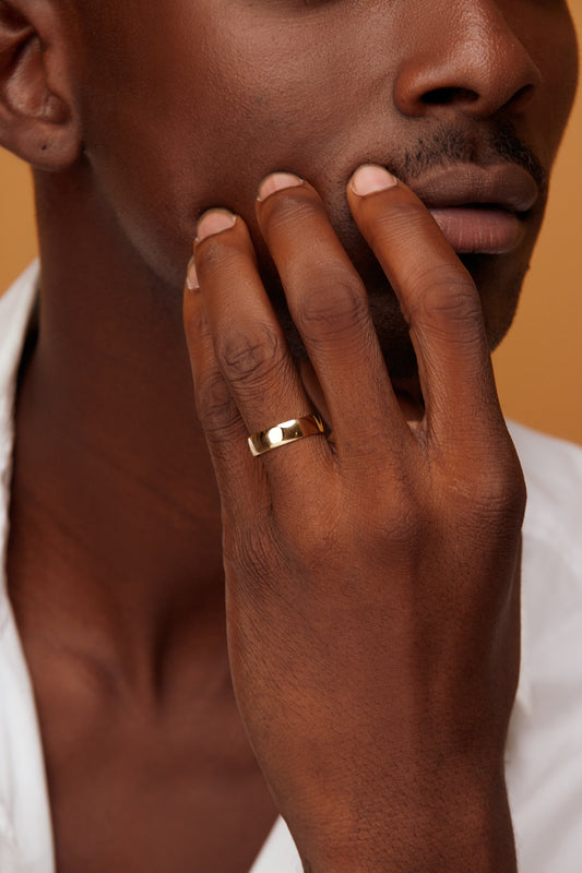 A man wearing a 10 karat gold band on his finger.