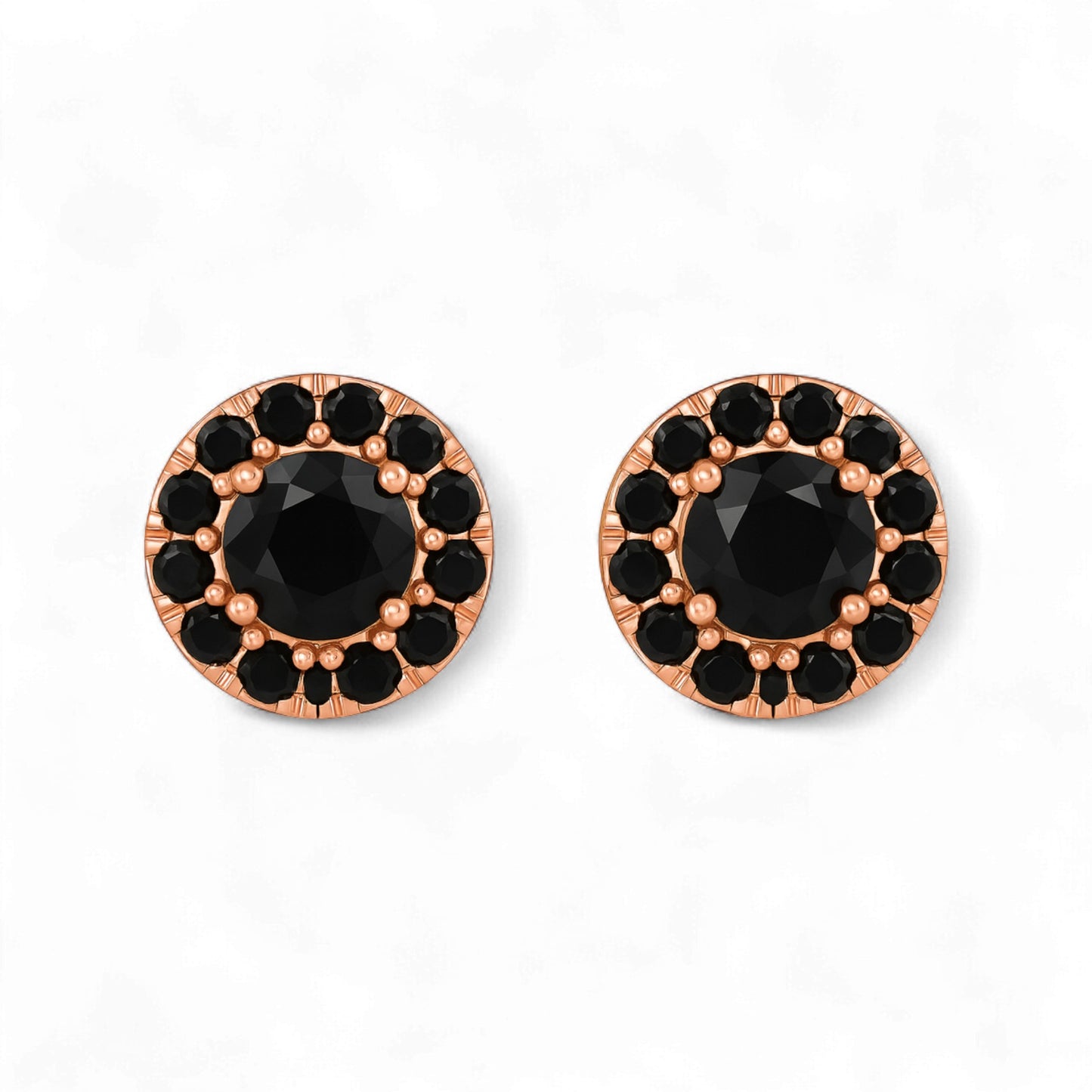 Pair of round earrings with black gemstones and rose gold frames on a white background