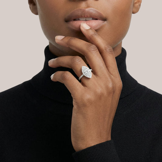 Hand wearing a diamond ring with a neutral background