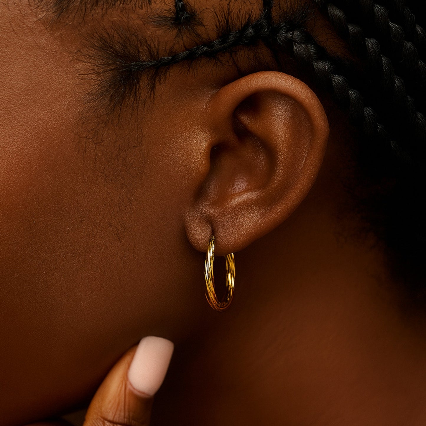 Close-up of an ear wearing a gold hoop earring with a blurred background
