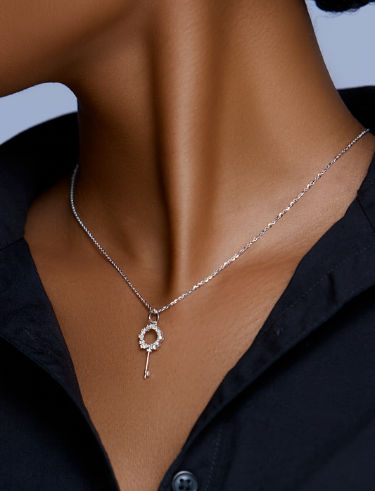 Necklace with a key pendant worn by a person against a neutral background