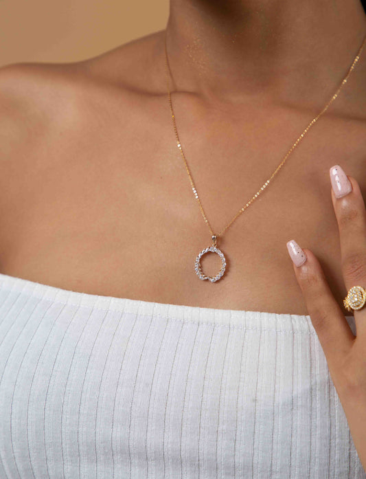 A woman wearing a gold-tone pendant with a round shape Moissanite gemstone.
