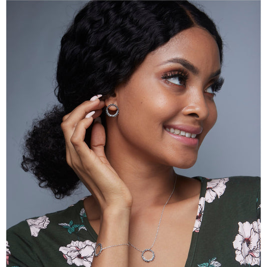 Woman wearing earrings and a necklace against a gray background