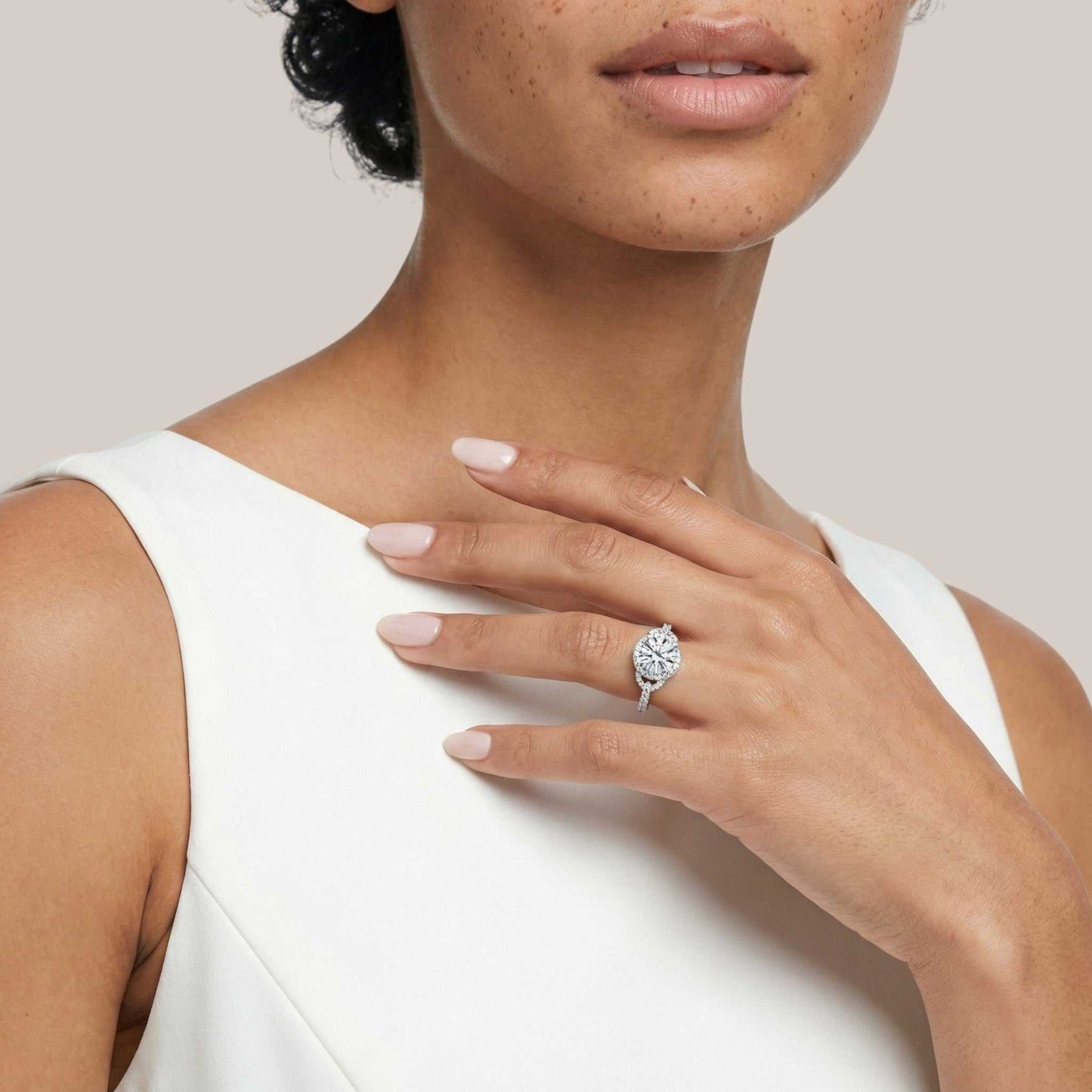 Woman wearing a diamond ring on her hand with a plain background