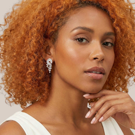 Woman with curly hair wearing a white top against a neutral background