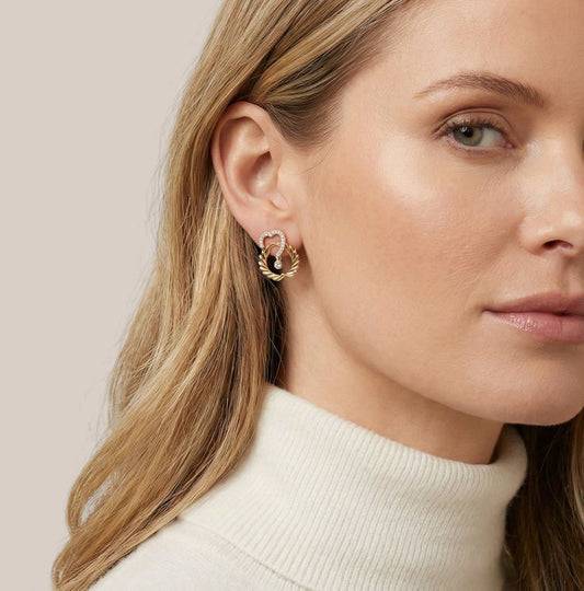 Close-up of a woman wearing gold hoop earrings with a neutral background