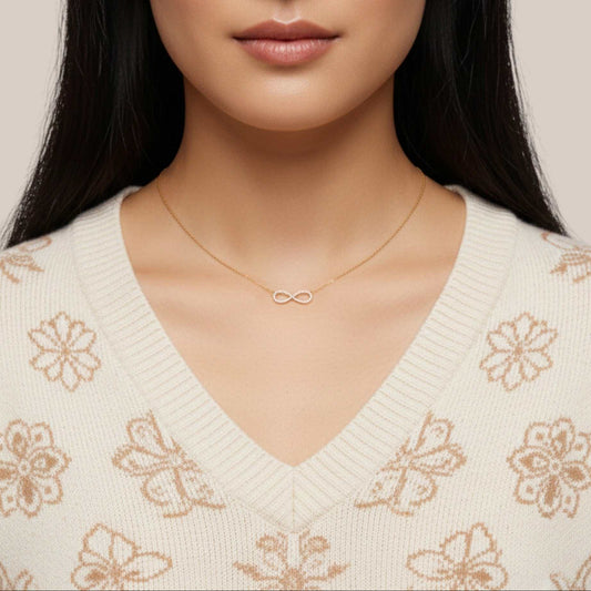 Woman wearing a gold necklace with an infinity symbol on a neutral background