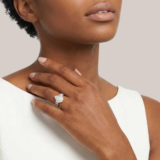 Close-up of a hand wearing a diamond ring on a neutral background