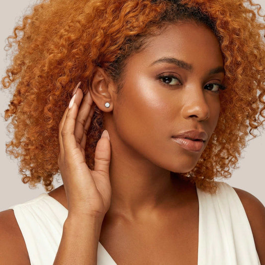 Woman with curly hair wearing a white top against a neutral background