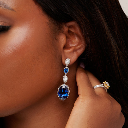 Close-up of a woman wearing a blue gemstone earring and ring.