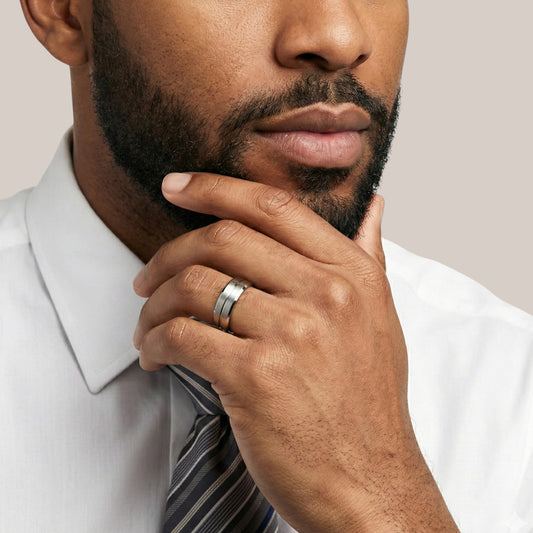 Man wearing a white shirt and striped tie with a close-up of his hand and ring.