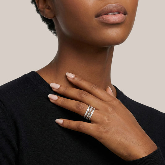 Close-up of a person wearing multiple rings on a plain background