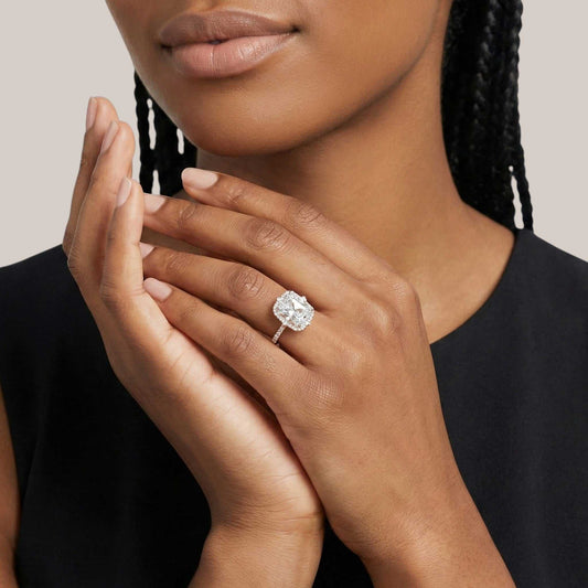 Woman wearing a diamond ring on her finger with a neutral background