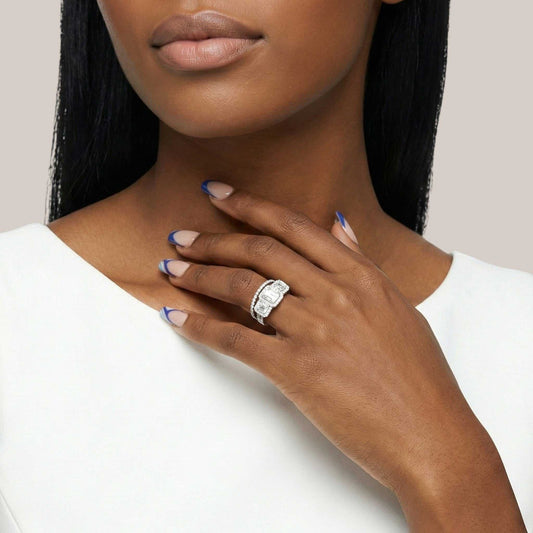 Woman wearing a silver ring with a large diamond on a plain background