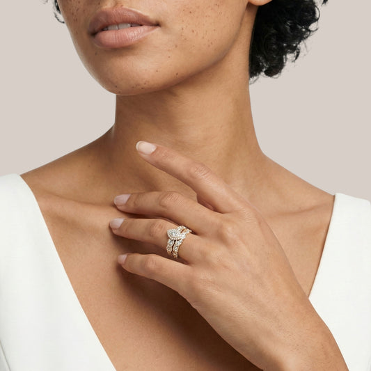 Close-up of a woman's hand wearing a diamond ring on a neutral background