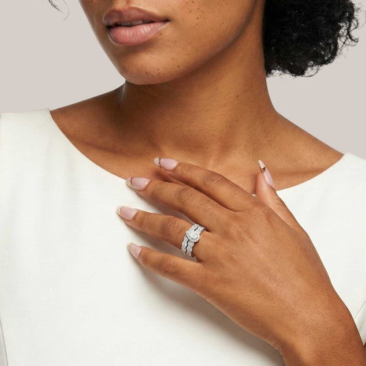 Close-up of a woman's hand wearing a diamond ring on a plain background