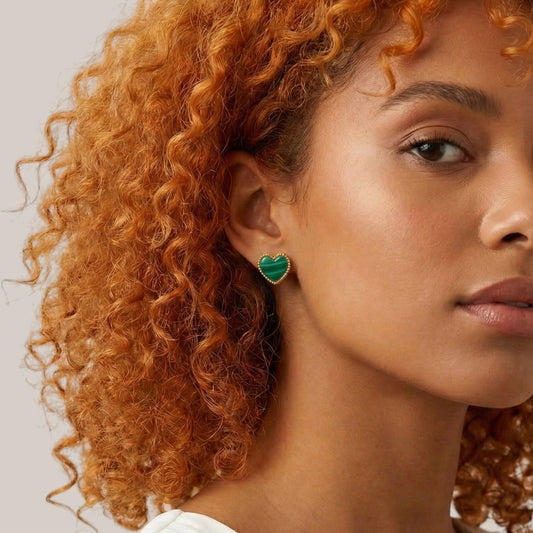 Close-up of a person with curly hair wearing a green heart-shaped earring.