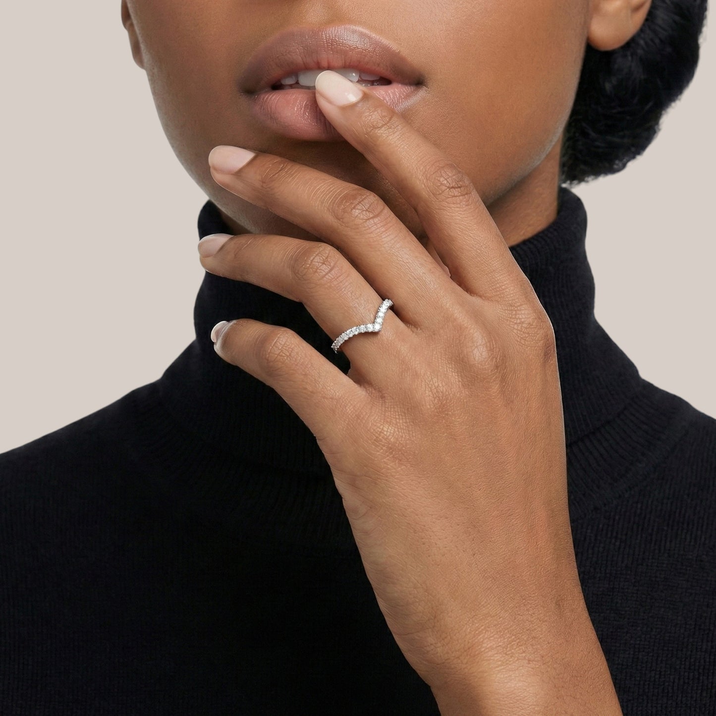 Close-up of a hand wearing a ring with a neutral background