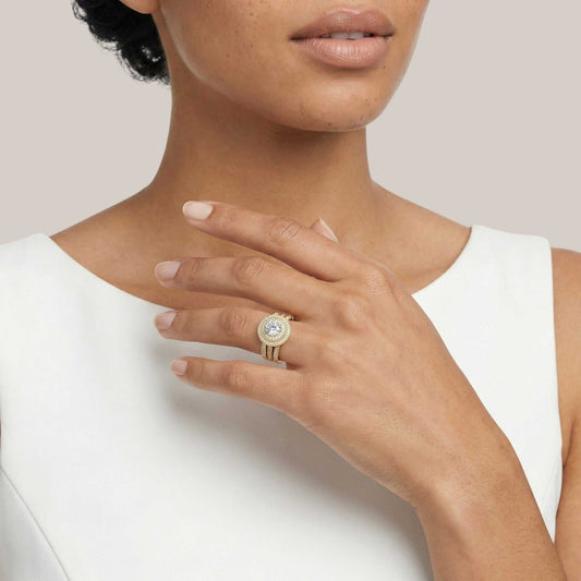 Close-up of a person wearing a gold ring with a diamond on a plain background