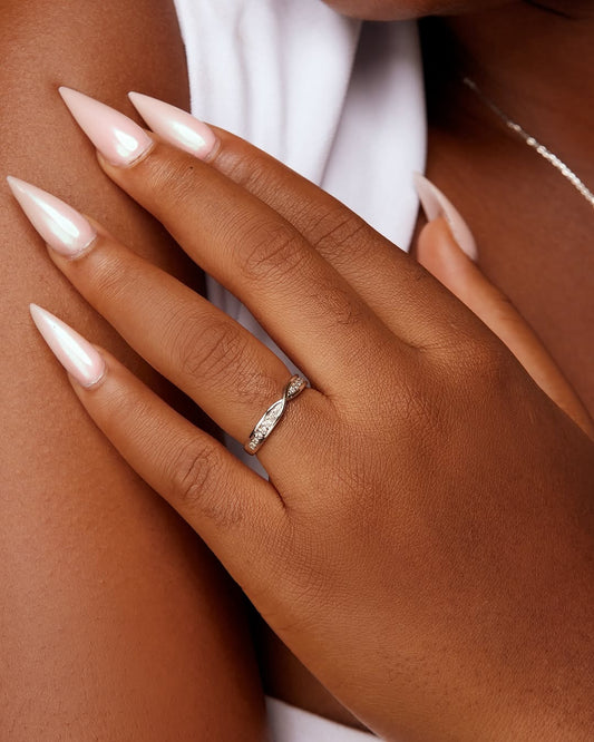 A person's hand displaying a gold band ring with natural diamonds.