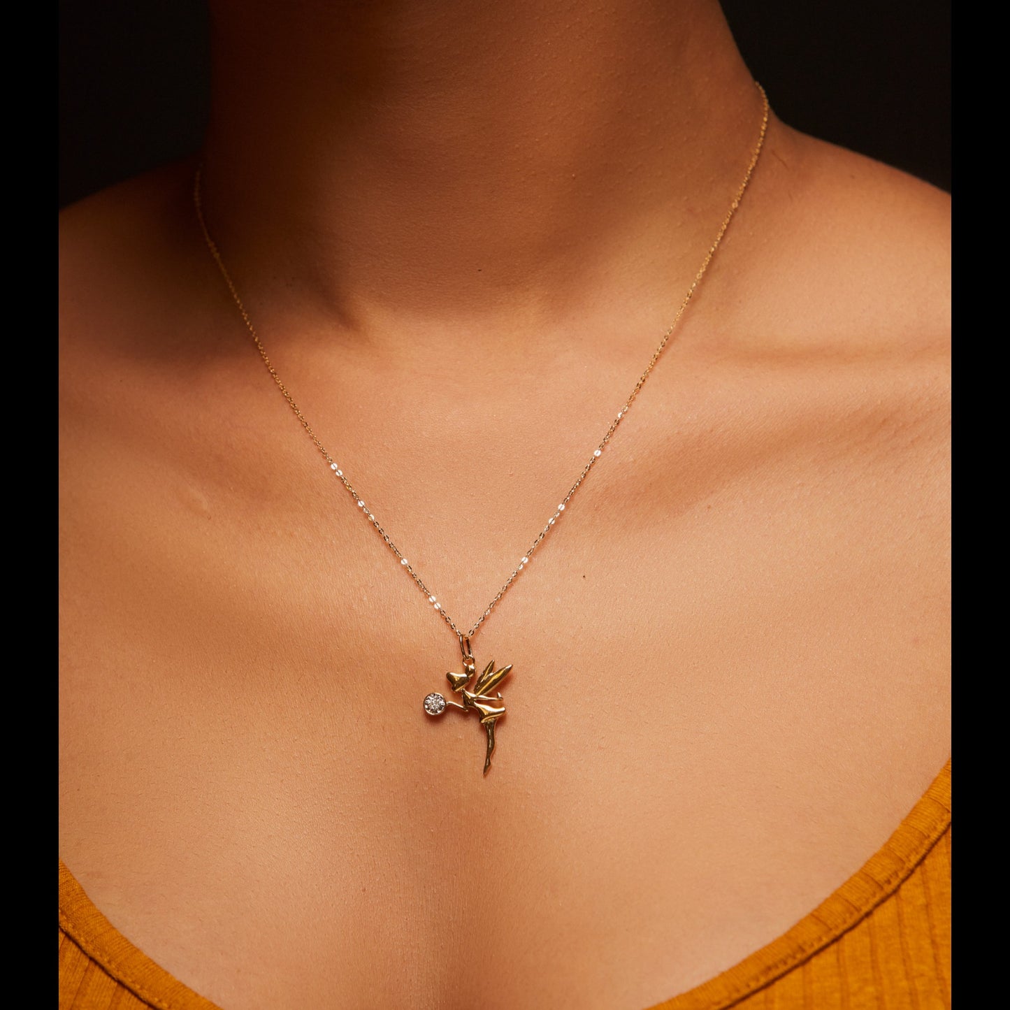 Necklace with a pendant on a person wearing an orange top against a dark background