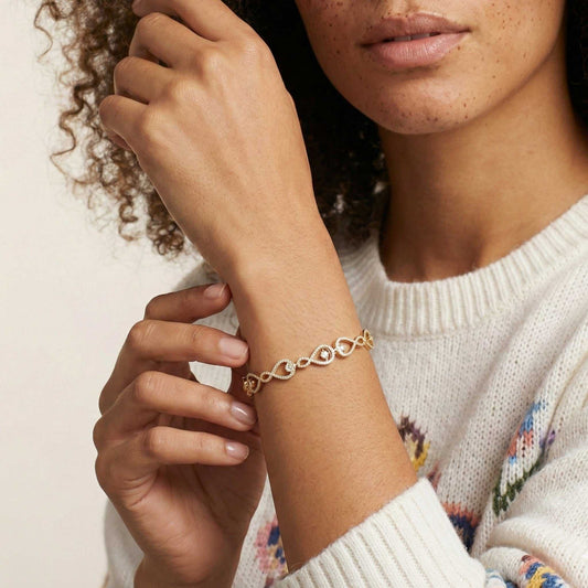 Woman wearing a gold bracelet on a neutral background
