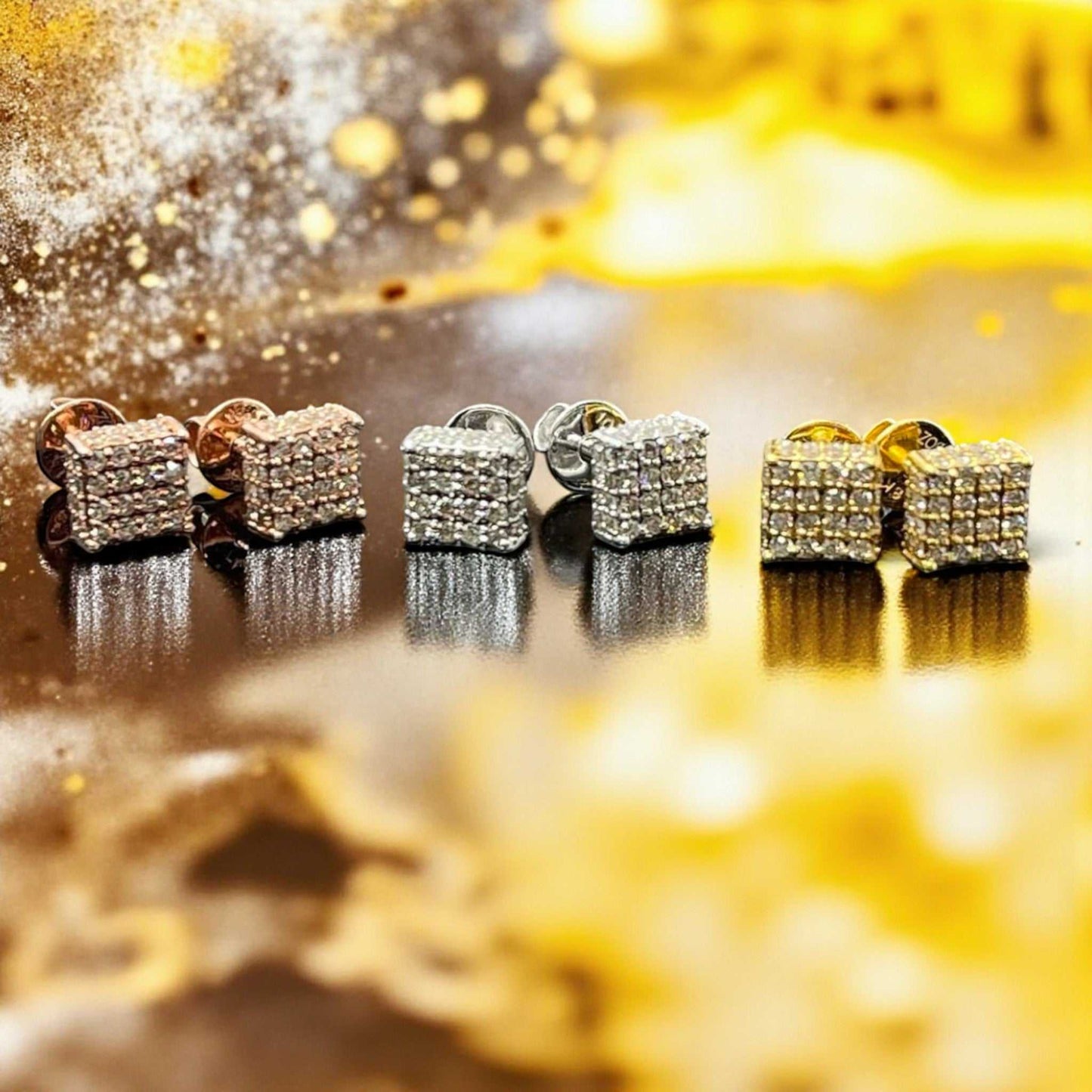 Pair of diamond-studded earrings on a reflective surface with a blurred gold background