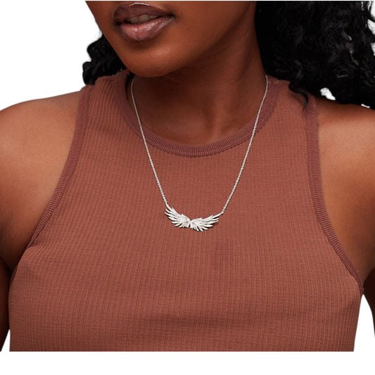 Woman wearing a brown tank top with a silver necklace featuring an angel wing pendant.