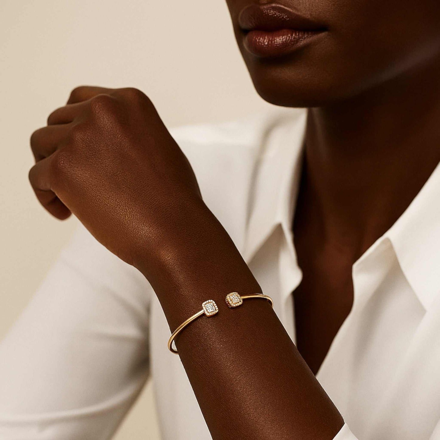 Woman wearing a gold bracelet with diamond accents on a neutral background