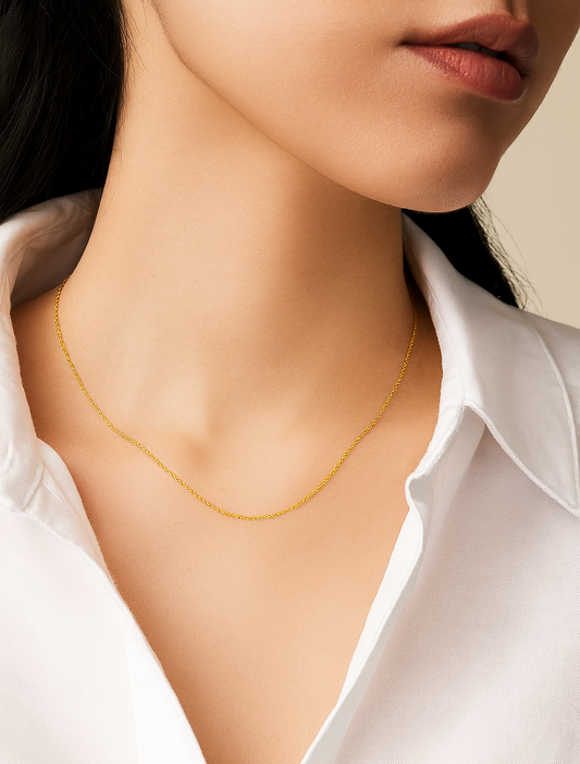 Close-up of a person wearing a delicate gold necklace with a white shirt.