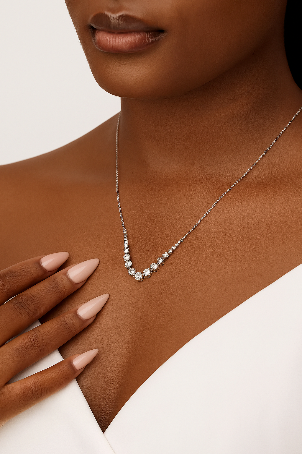 Necklace with small stones worn by a person, with a focus on the jewelry.