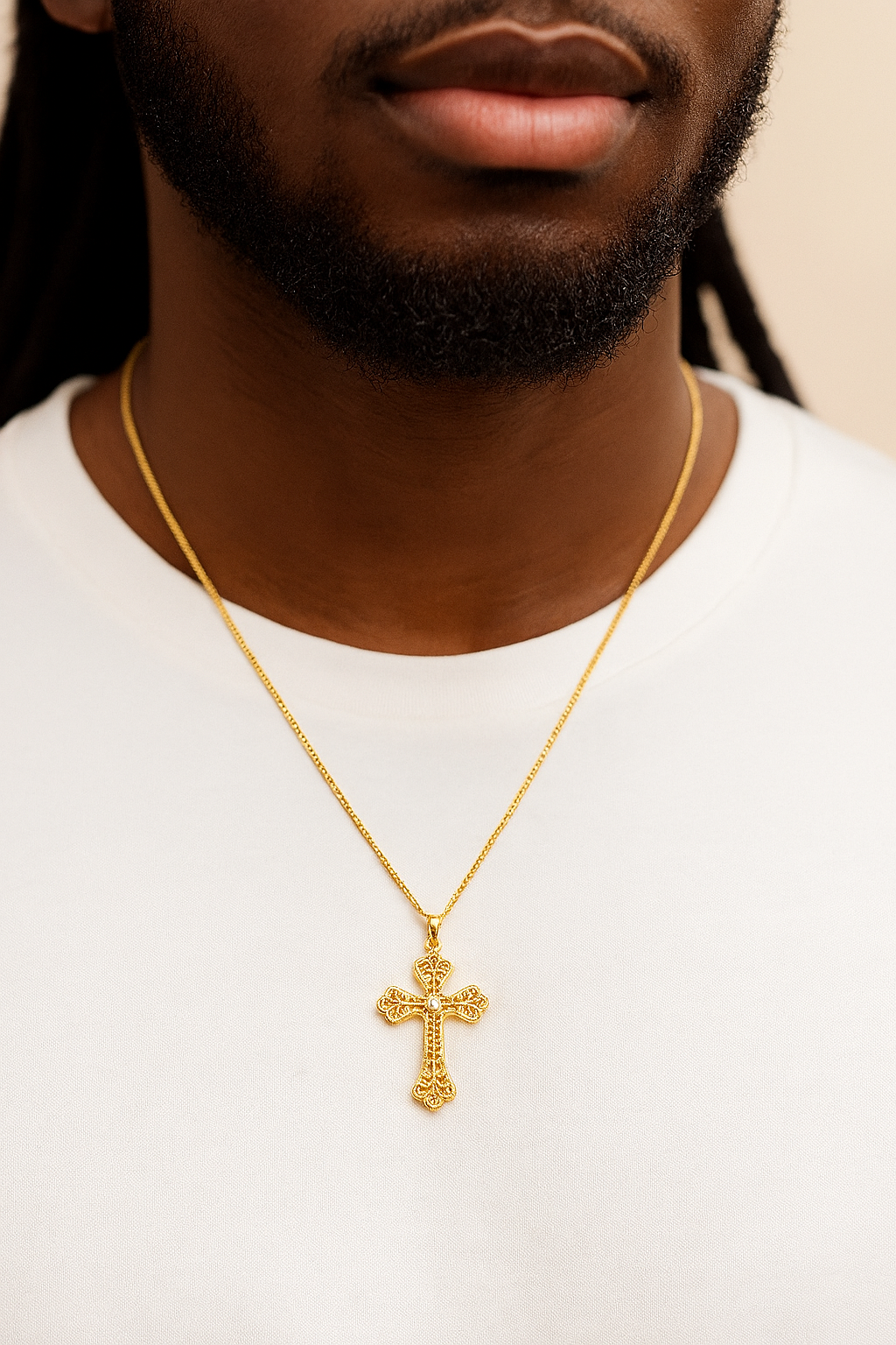Gold cross necklace worn by a person on a white background