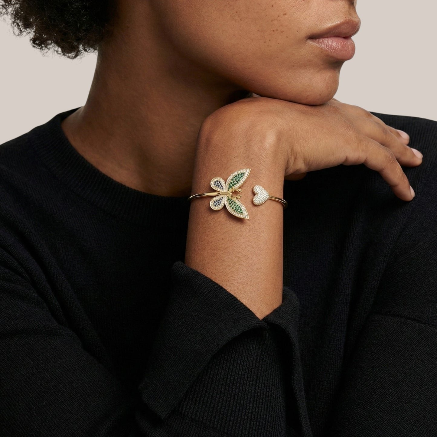 Person wearing a bracelet with leaf design on a neutral background