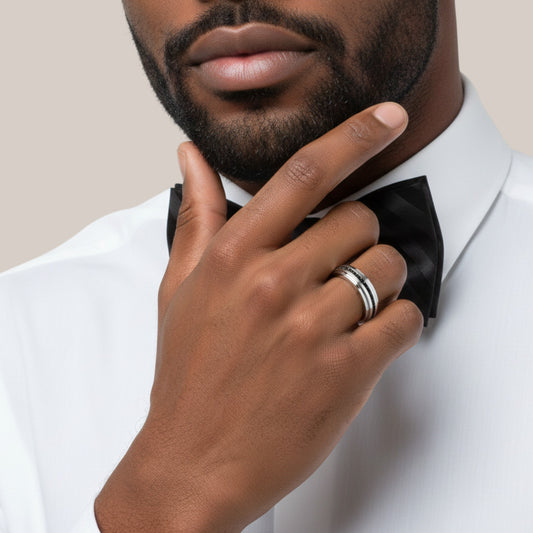 Man adjusting a black bow tie on a white shirt against a neutral background