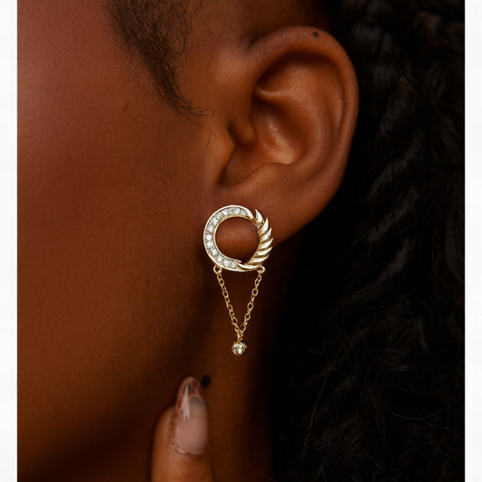 Gold earring with a circular design worn by a person