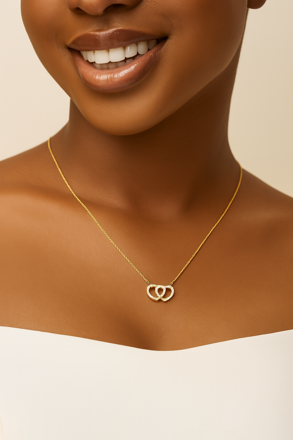 Gold necklace with a heart pendant worn by a model on a beige background