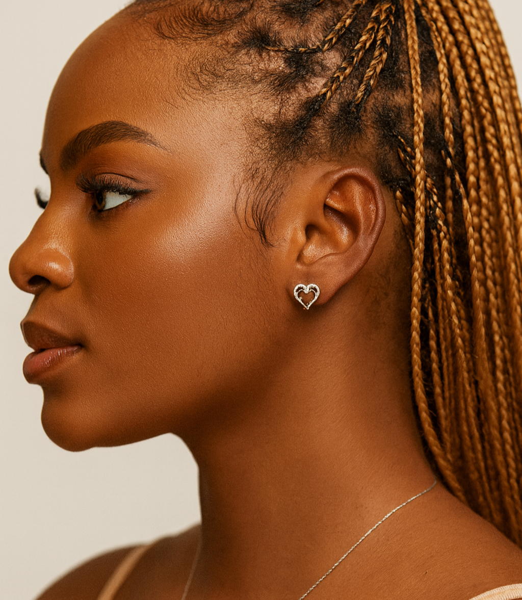 Woman with braided hair wearing a heart-shaped earring and necklace on a neutral background