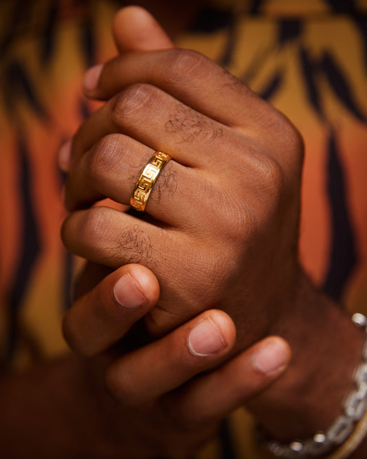 A person's hand wearing a 10 karat gold band ring.